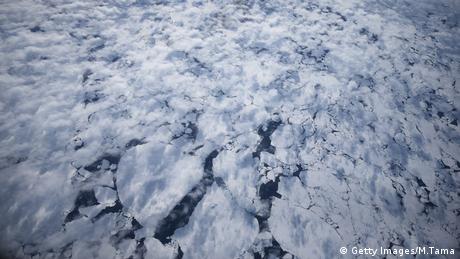 Broken sea ice can be seen through light cloud cover mid-flight during last season